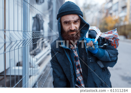 Male bearded beggar with bag on city street 61311284