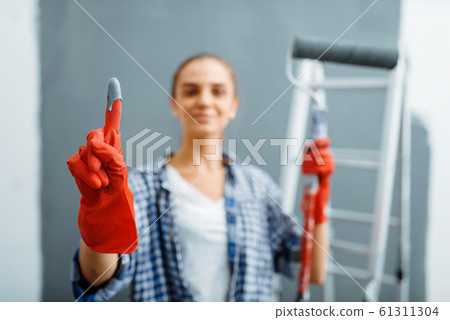 Young woman shows glove in paint, home repair 61311304