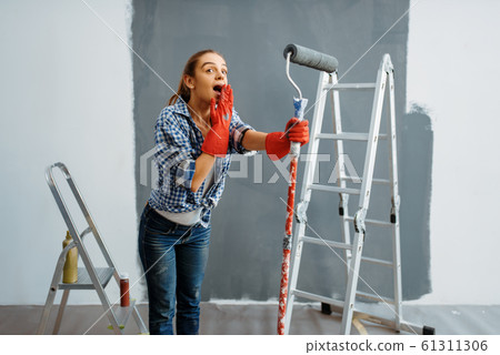Surprised young woman makes home repair 61311306