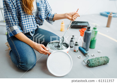 Female house painter mixes paints in pail 61311357