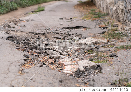 asphalt road destroyed by holes and washed out by 61311460