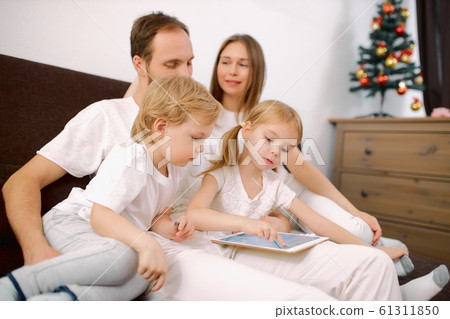 caucasian family use tablet at home sitting on sofa 61311850