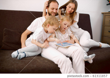 friendly family in casual clothes sit on sofa at home using tablet 61311857