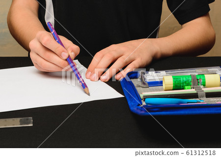 A schoolboy draws pencils on white paper. 61312518