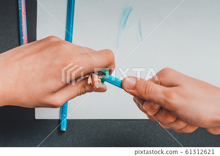 The sharpener sharpens his pencils for drawing. 61312621