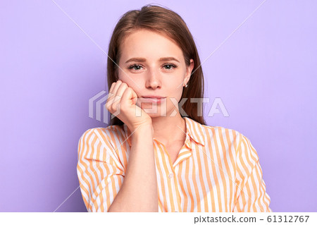 Cute female student keeps hand under chin, feels tired and bored at lesson 61312767