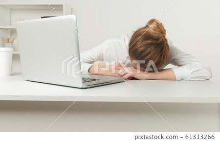 Overworked and tired sleeping over a laptop in a desk at work in her Overworked and tired sleeping over a laptop in a desk at work in her 61313266
