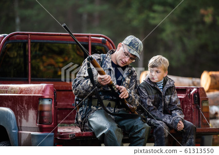 Father teaches his grandson to hunt in a woods 61313550