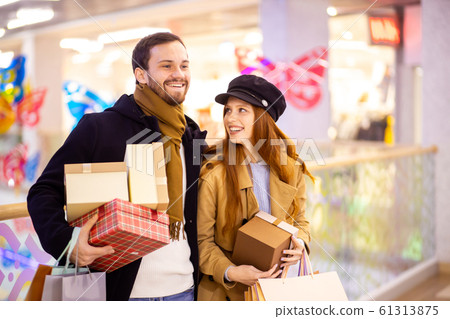 beautiful caucasian couple after shopping holding gifts in mall beautiful caucasian couple after shopping holding gifts in mall 61313875