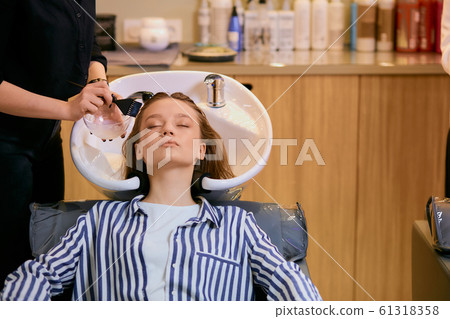 young woman dyeing hair in beauty saloon 61318358