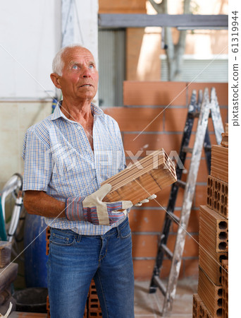 Man inspecting brick for installing wall Man inspecting brick for installing wall 61319944