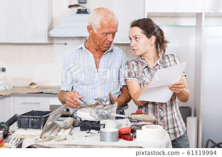 Woman and father discussing instructions for mixer tap 61319994