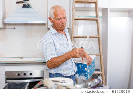 Senior man puttying walls 61320019