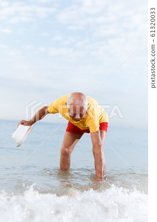Modern elderly man touches the water temperature 61320033