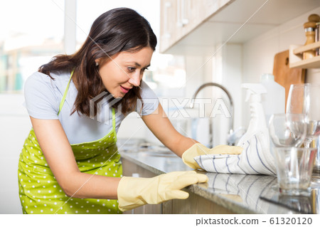 Girl housewife in apron cleaning furniture at kitchen at home Girl housewife in apron cleaning furniture at kitchen at home 61320120