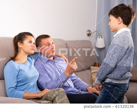 Portrait of offended boy after quarrel with parents sitting on sofa at home Portrait of offended boy after quarrel with parents sitting on sofa at home 61320136