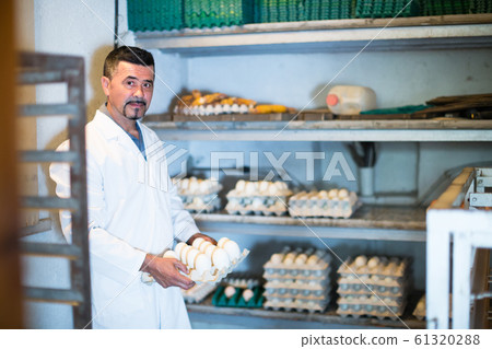 Man packing hen eggs in farmhouse. 61320288