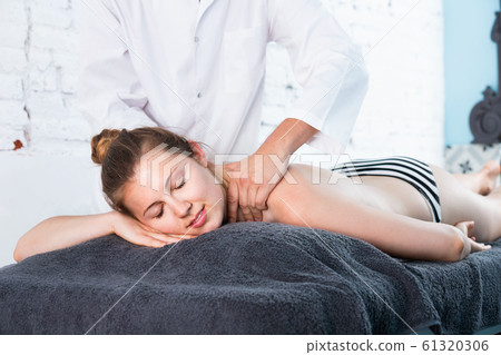 Woman massage therapist massaging relaxing young woman 61320306