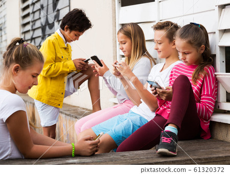 Five kidsare chatting on their smartphone Five kidsare chatting on their smartphone 61320372