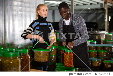 Man and woman stacking plastic buckets with pickled olives Man and woman stacking plastic buckets with pickled olives 61320441