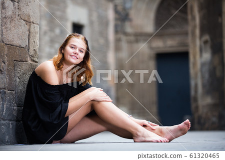 Cheerful girl sitting barefoot near the brick wall 61320465