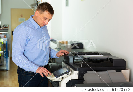 Worker is printing a file, document in the office room Worker is printing a file, document in the office room 61320550