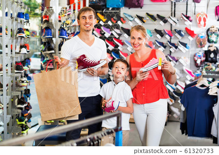 Cheerful young parents with boy in school age shopping shoes Cheerful young parents with boy in school age shopping shoes 61320733