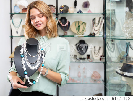 Girl showing pearl necklace on stand 61321190