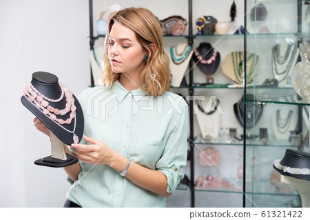 Saleswoman demonstrating beads from pink aventurine 61321422