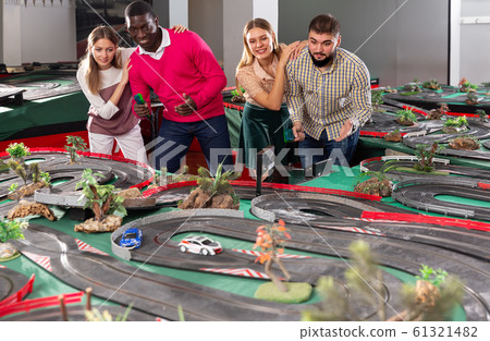 Two teams from couples play slot car racing game 61321482