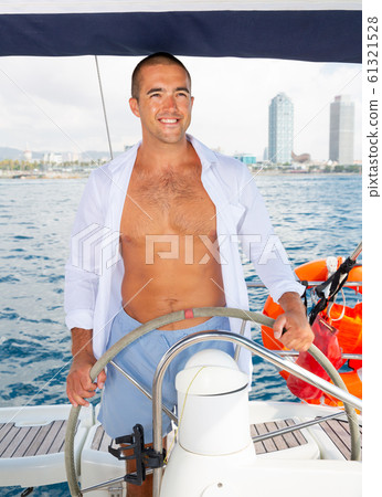 Man standing at yacht wheel 61321528