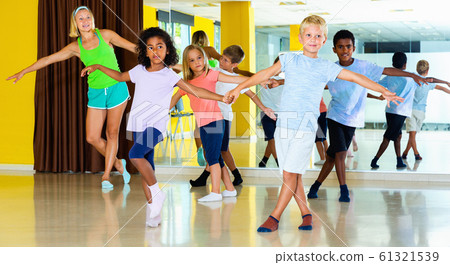Group of children practicing vigorous jive movements in dance cl 61321539