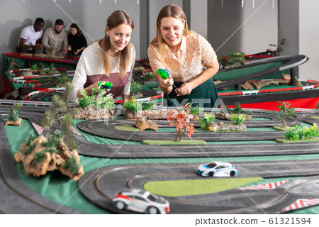 Emotional portrait of two women holding remote control and playing slot car racing Emotional portrait of two women holding remote control and playing slot car racing 61321594