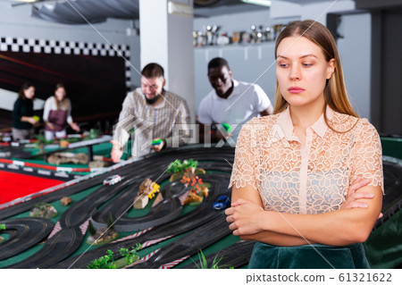 Upset woman, friends playing with race cars Upset woman, friends playing with race cars 61321622