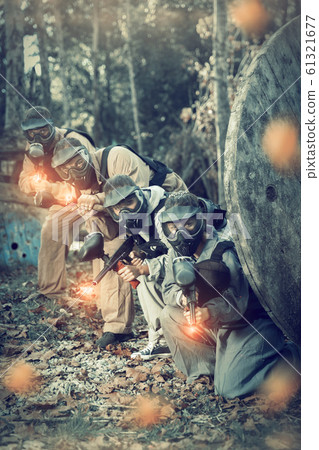 Paintball players shooting with guns 61321677