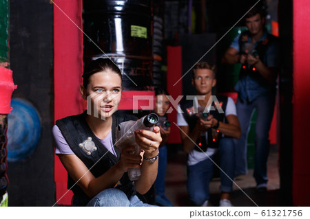 Portrait of young girl took aim colored laser guns during laser tag game in labyrinth 61321756