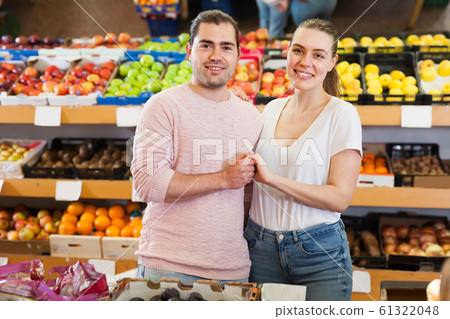 Glad family couple standing near fruits Glad family couple standing near fruits 61322048