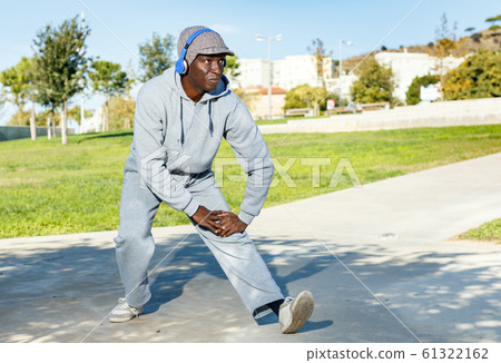 Athletic african american male performs warm-up exercises in park Athletic african american male performs warm-up exercises in park 61322162