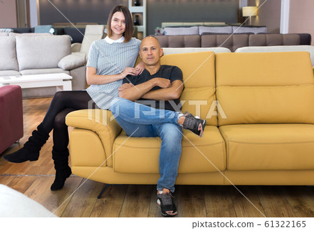 Husband and wife sitting on bright yellow couch Husband and wife sitting on bright yellow couch 61322165