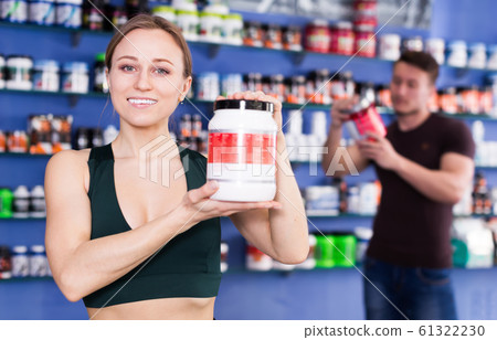 Smiling sporty female with jar of sports supplements products 61322230