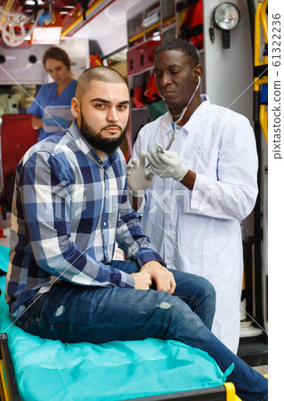 Emergency doctors providing first aid to man in ambulance auto Emergency doctors providing first aid to man in ambulance auto 61322236