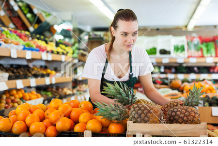 Young woman wearing apron working with fresh pineapples 61322314