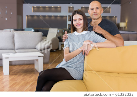 Husband and wife sitting on bright yellow couch 61322322