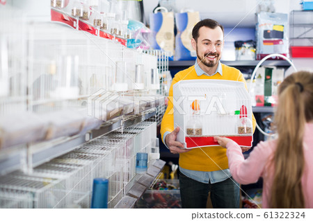 man seller demonstrating canary bird in cage to girl in pet shop man seller demonstrating canary bird in cage to girl in pet shop 61322324