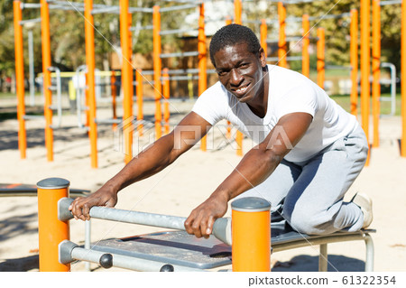 Active african american man doing workout at pull-up bar in park 61322354