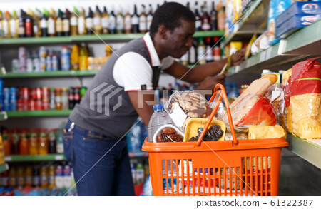 Man with shopping cart full of goods Man with shopping cart full of goods 61322387