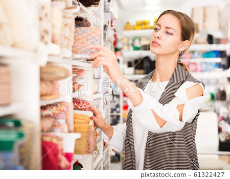 Seamstress looking for ribbons in haberdasher shop Seamstress looking for ribbons in haberdasher shop 61322427