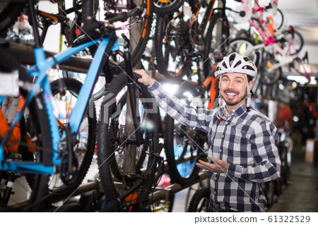 man in helmet chooses for himself sports bike in bicycle shop 61322529