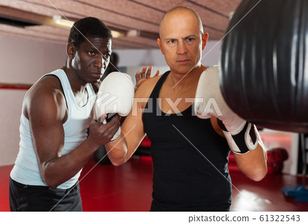 African american trainer teaches man in boxing 61322543