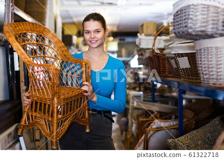 woman standing with wicker chair in shop for decor 61322718